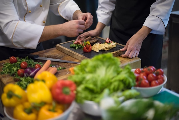 Professional team cooks and chefs preparing meal at busy hotel or restaurant  kitchen