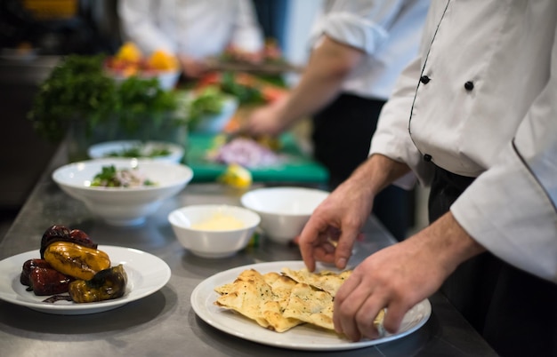 Professional team cooks and chefs preparing meal at busy hotel or restaurant  kitchen