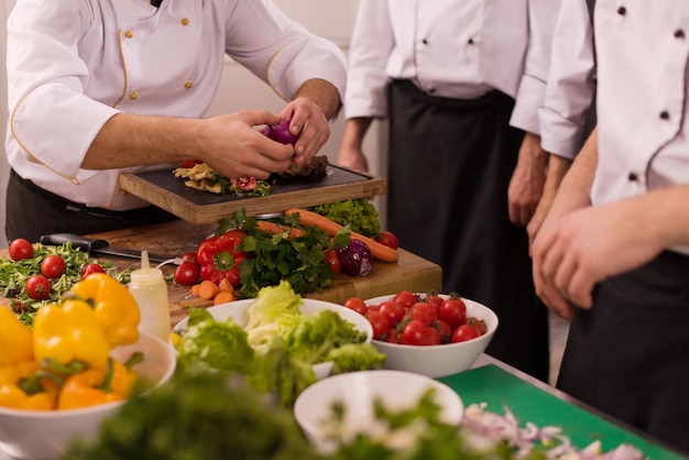 Professional team cooks and chefs preparing meal at busy hotel or restaurant  kitchen