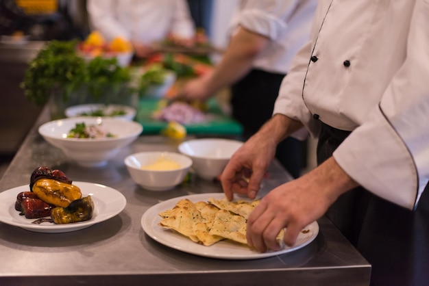 Professional team cooks and chefs preparing meal at busy hotel\
or restaurant kitchen