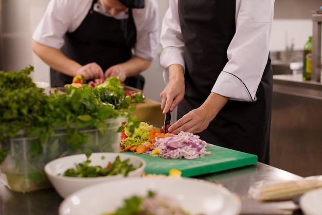 Professional team cooks and chefs preparing meal at busy hotel\
or restaurant kitchen