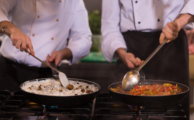 忙しいホテルやレストランのキッチンで食事を準備するプロのチーム料理人とシェフ