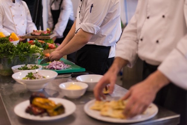 Foto cuochi e chef di squadra professionisti che preparano pasti nella cucina di un hotel o di un ristorante affollato