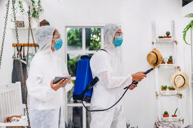 보호 마스크 및 흰색 정장 소독제 스프레이 청소 바이러스 소독 작업자 전문 팀