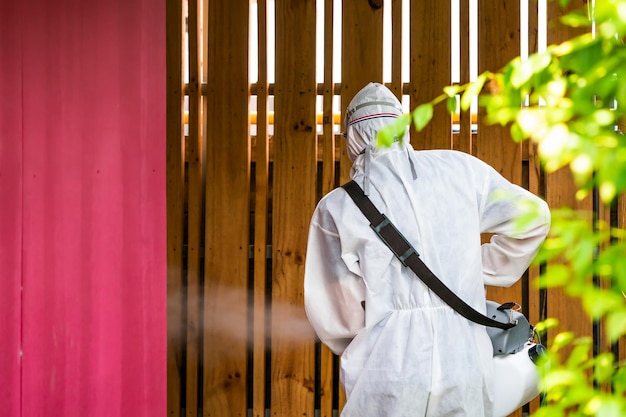 Professional technical man in prevention suit with his sterilizing machine and disinfecting water sprays in the outdoor field for purifying coronavirus COVID19