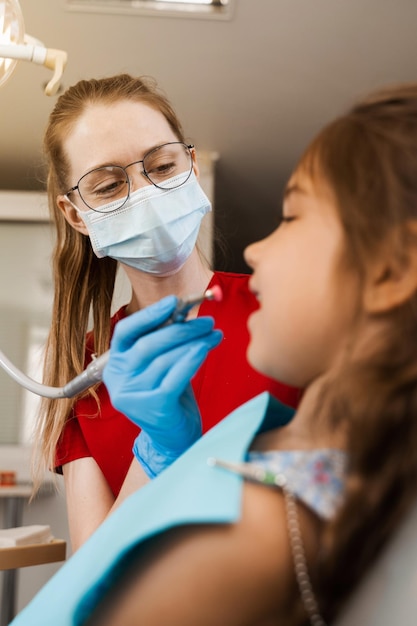 Professional teeth cleaning for child girl in dentistry Professional hygiene for teeth of child Pediatric dentist examines and consults kid patient in dentistry