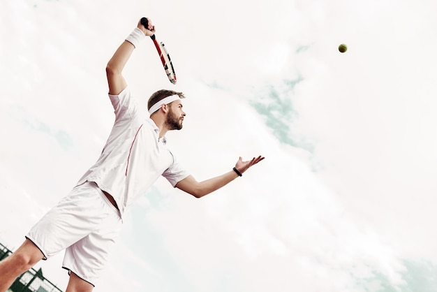 Professional tennis player is doing a kick tennis on a tennis court on a sunny