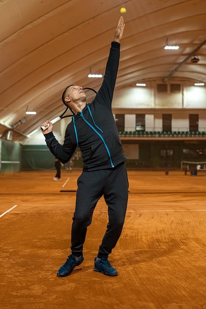 Professional tennis player is hitting tennis on an indoor tennis court from early morning