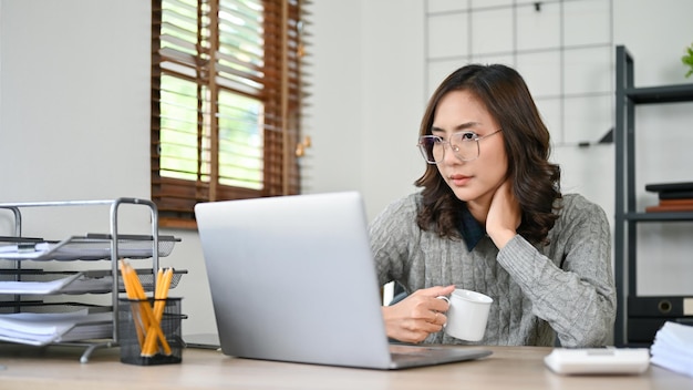 Professional and thoughtful Asian businesswoman focusing looking at laptop screen