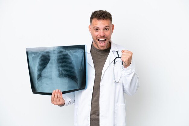 Professional traumatologist caucasian man isolated on white background celebrating a victory in winner position