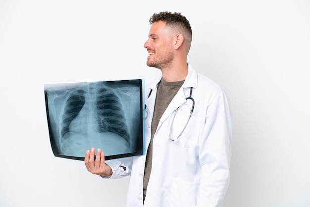 Professional traumatologist caucasian man isolated on white background laughing in lateral position