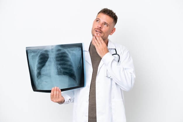 Professional traumatologist caucasian man isolated on white background looking up while smiling