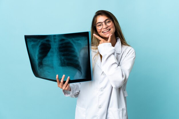 Professional traumatologist isolated on blue wall happy and smiling