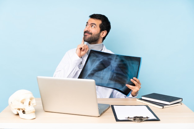 Professional traumatologist in workplace thinking an idea while\
looking up