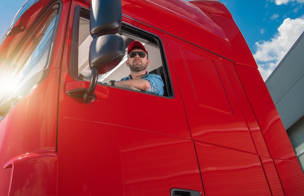 Professional Trucker Behind the Semi Tractor Truck Wheel