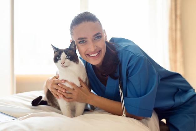 Professional veterinarian lady embracing healthy cat at vet clinic