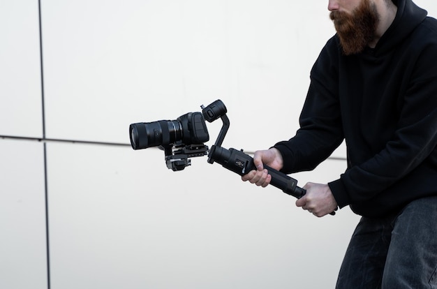 Professional videographer in black hoodie holding professional camera