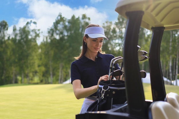 Professional woman golf player choosing the golf club from the\
bag.