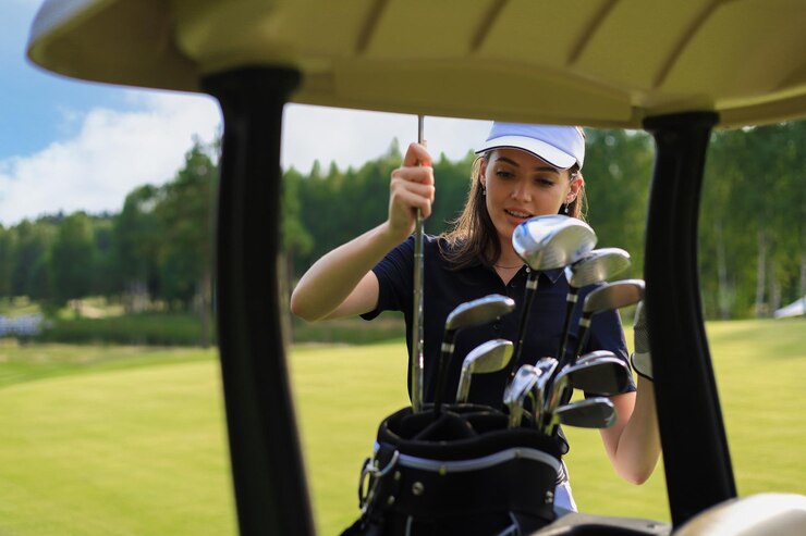 Photo バッグからゴルフクラブを選ぶプロの女性ゴルフプレーヤー。