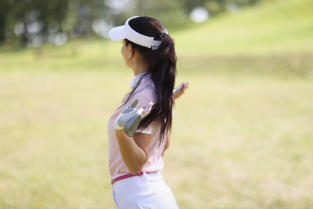 전문 여성 골프 선수가 필드에 골프 클럽을 들고 포즈를 취합니다.