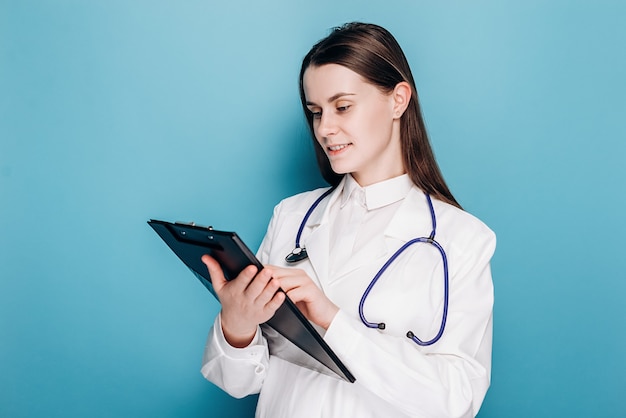 Professional woman physician specialist in white coat, writing down symptoms