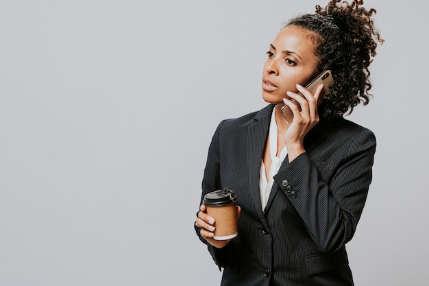 コーヒーとスマートフォンを持つプロの女性