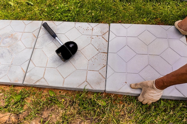 Профессиональный рабочий укладывает каменные плиты на территории загородного дома, озеленение и ландшафт придомовой территории