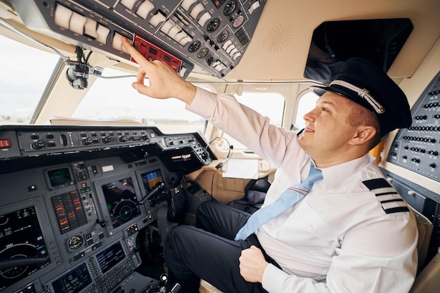 Professional worker Pilot in formal wear sits in the cockpit and controls airplane