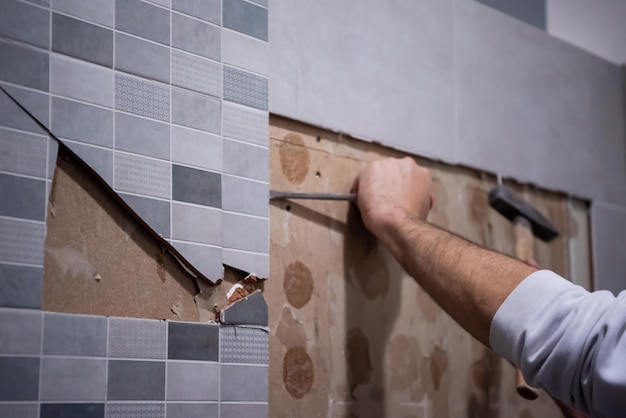 Photo professional worker remove demolish old tiles in a bathroom with hammer and chisel