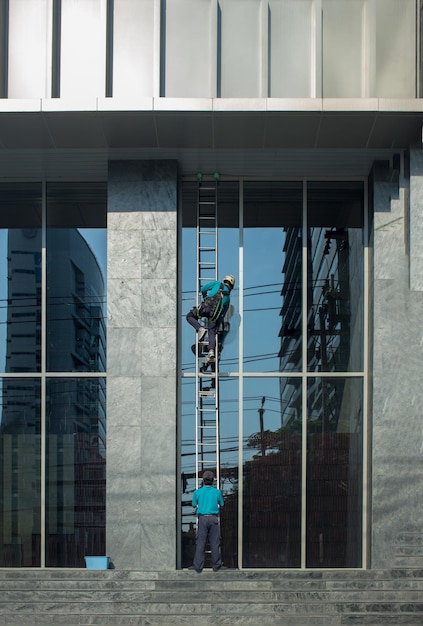 Photo professional workers with wash tools on mirror exterior building panels