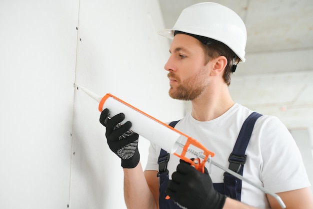 Professional Workman Applying Silicone Sealant With Caulking Gun on the Wall