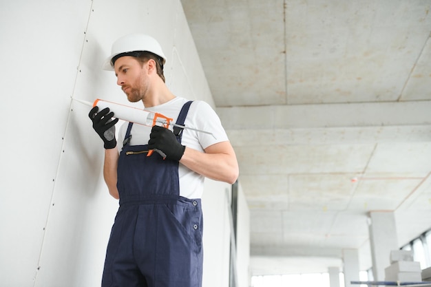 Professional Workman Applying Silicone Sealant With Caulking Gun on the Wall