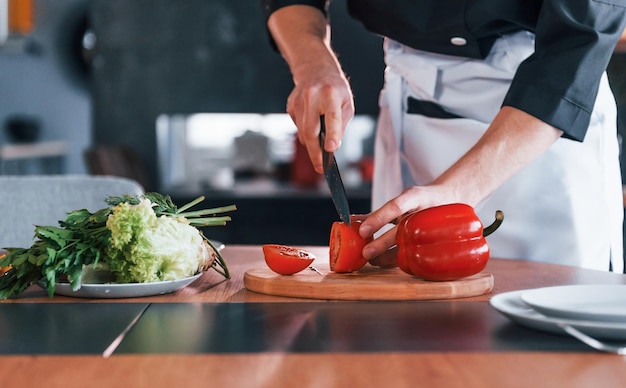 Giovane cuoco professionista in uniforme che fa insalata in cucina