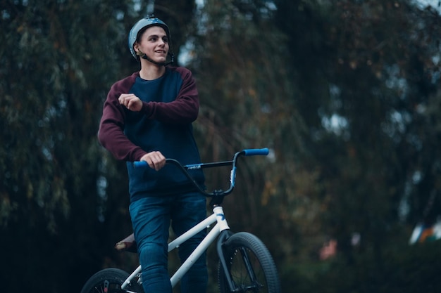 Профессиональный молодой спортсмен в шлеме, велосипедист с велосипедом bmx в скейтпарке