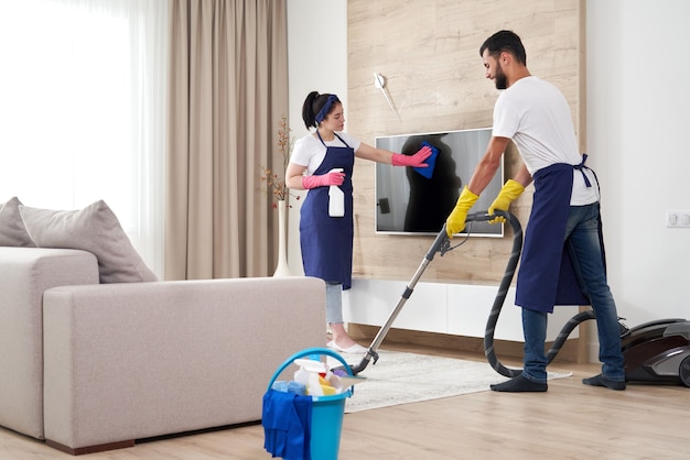 Professioneel schoonmaakserviceteam reinigt woonkamer in modern appartement