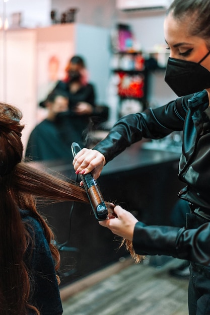 Professioneel stijlvol met behulp van stijltangen op het haar van klanten bij schoonheidssalon