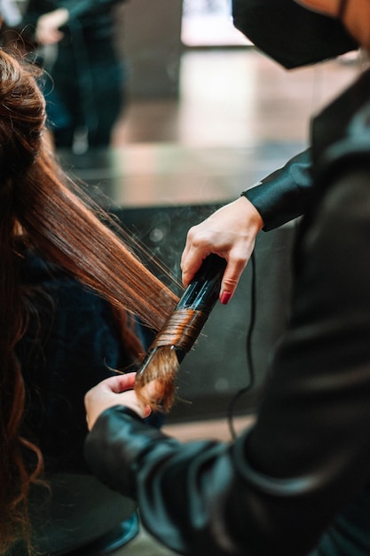 Professioneel stijlvol met behulp van stijltangen op het haar van klanten bij schoonheidssalon