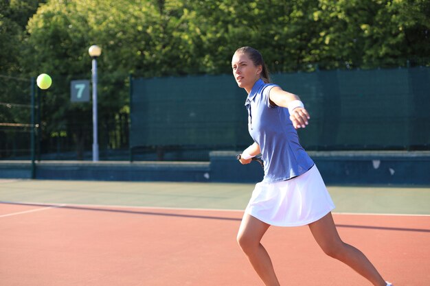 Professioneel uitgeruste tennisspeelster die de tennisbal hard slaat met racket.