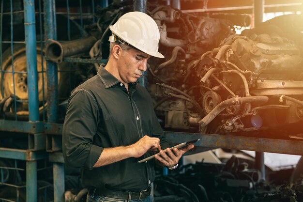 Professioneel volwassen ingenieur-mannetje dat dienstplicht bijwoont in fabriekswerkzaamheden die voorraadinventarisgegevens controleren met tabletcomputer