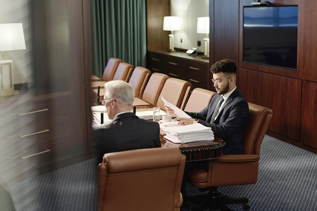 Foto professionele advocaten die met documenten werken, naast elkaar aan het bureau zitten