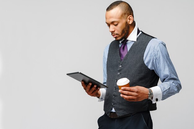 Professionele afro-amerikaanse zakenman met tablet pc en kopje koffie.