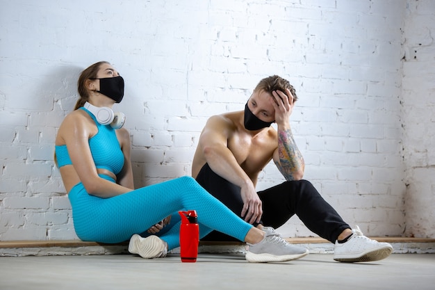 Professionele atleten die op bakstenen muurachtergrond trainen die gezichtsmasker dragen. sporten tijdens quarantaine