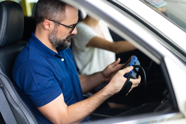 Professionele automonteur reparatieservice en het controleren van de motor van een auto door de computer van Diagnostics Software. Expertise monteur werkzaam in auto reparatie garage.