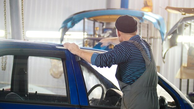 Professionele autoservice een werknemer polijst een blauwe auto