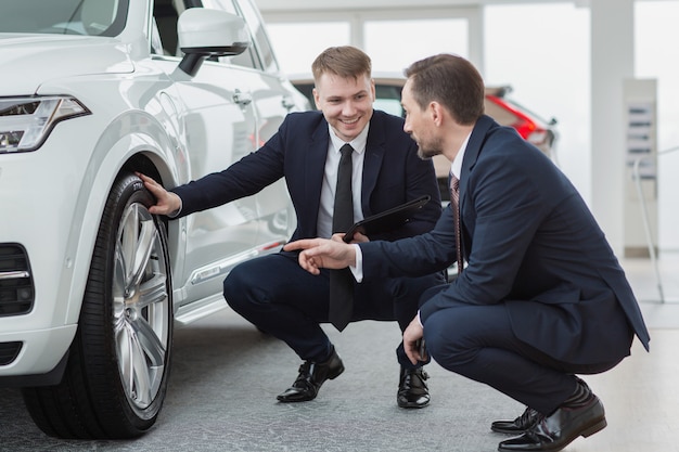 Professionele autoverkoper die zijn cliënt helpen die een nieuwe auto kiezen