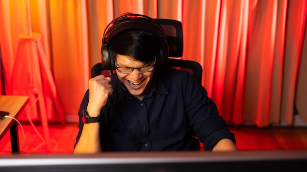 Professionele Aziatische mannelijke gamer die videogames speelt op een pc-computer Kleurrijke neonlichtruimte Esport online game