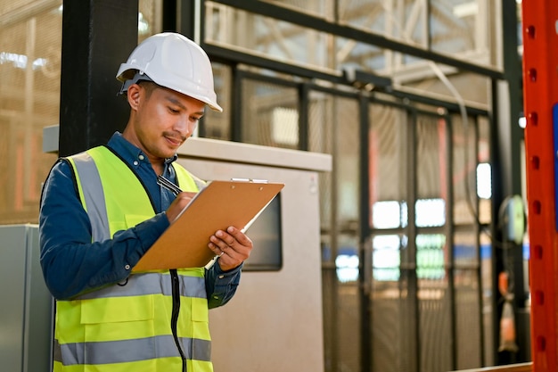 Professionele Aziatische mannelijke industrieel ingenieur of magazijningenieur die in magazijn of fabriek werkt