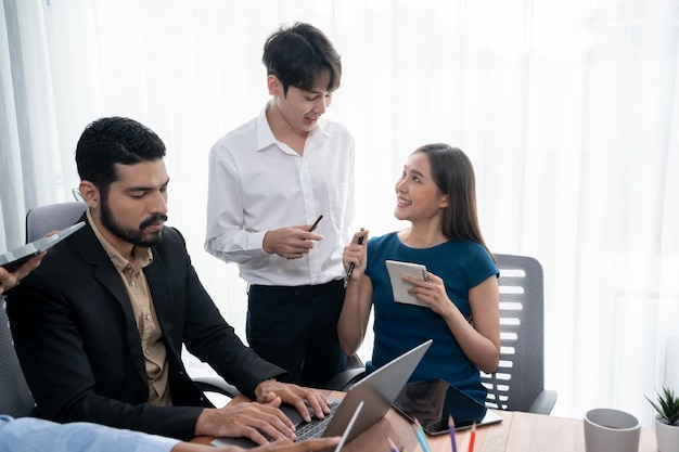 Professionele Aziatische werknemers werken samen als een team in het kantoor van het bedrijf en bespreken bedrijfsplannen en gegevens om succes te behalen op het bureau met een laptop Modern kantoormedewerker teamwerkconcept Concord