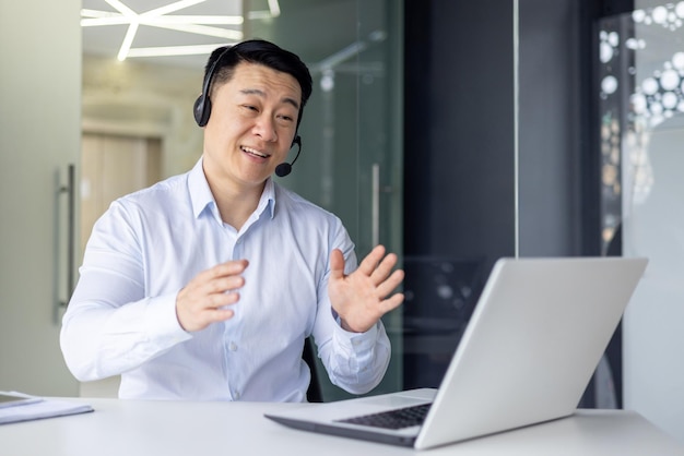 Professionele Aziatische zakenman in een headset bezig met een videogesprek die met handgebaren uitlegt in