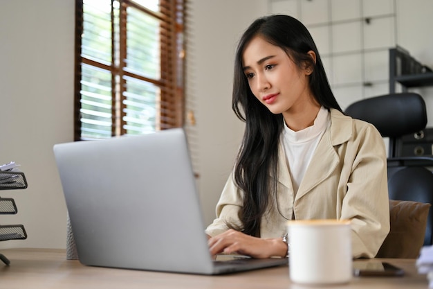 Professionele Aziatische zakenvrouw concentreerde zich op haar financiële online rapport op haar laptop